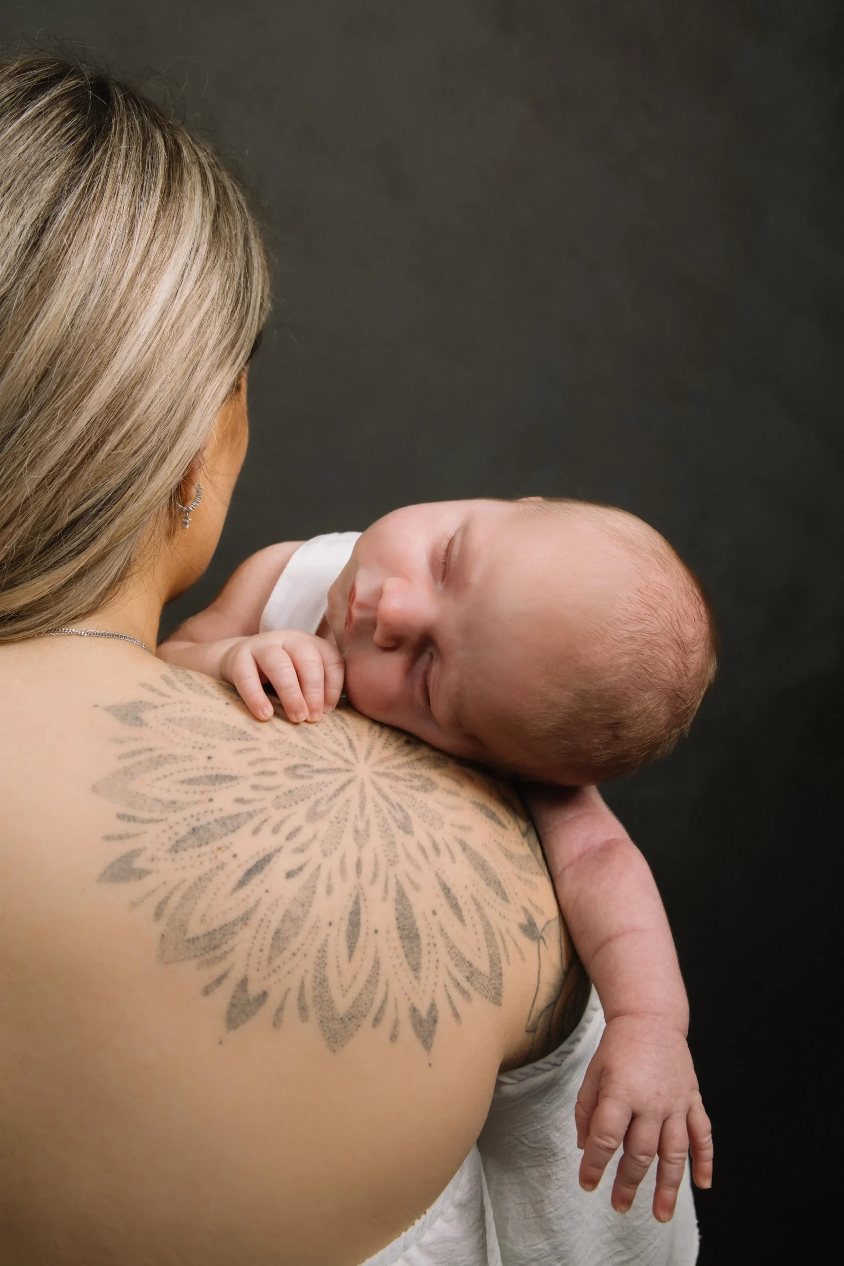 moeder met newborn Pasgeboren baby ligt ontspannen op de schouder van moeder tijdens een newborn fotoshoot.